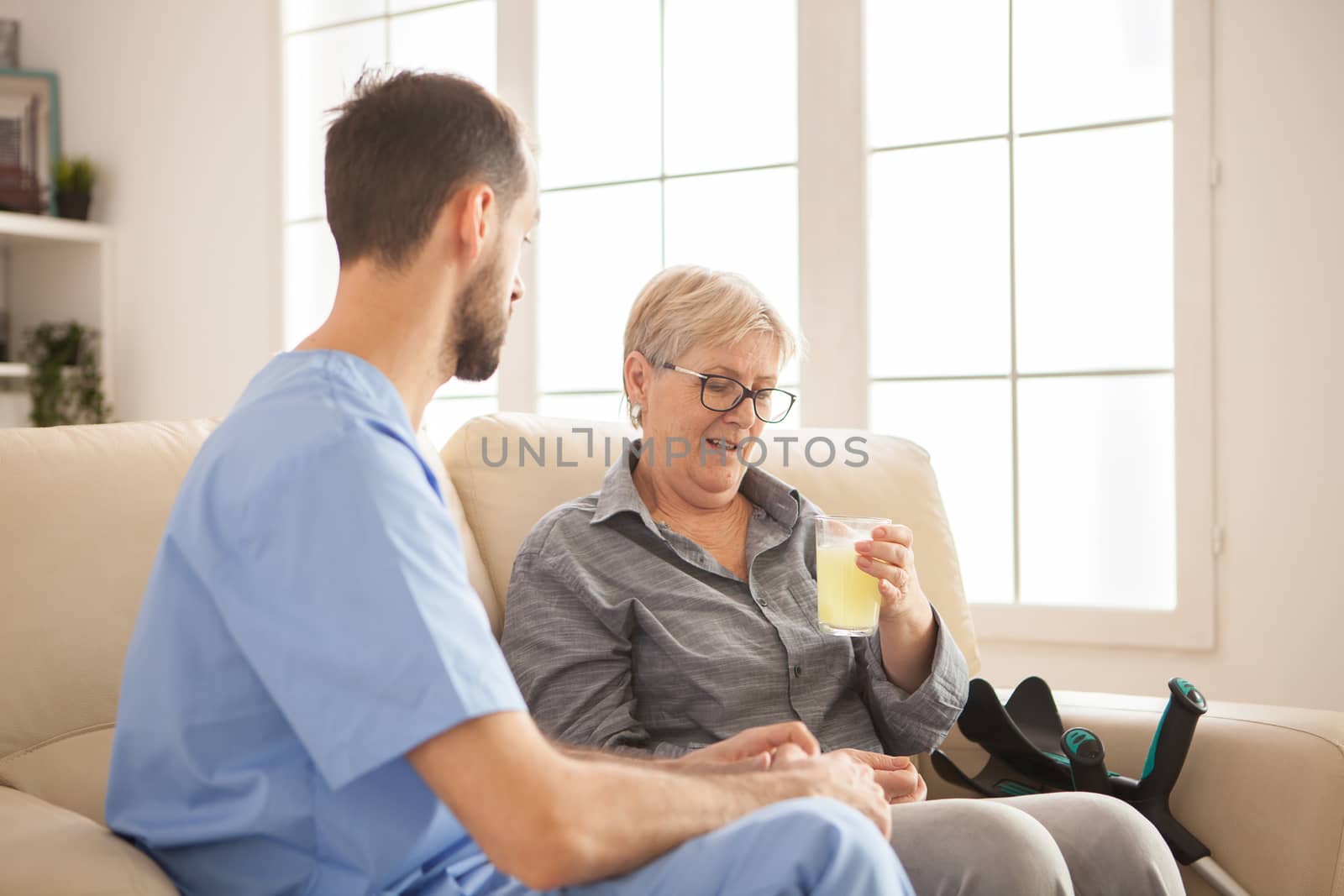 Male doctor helping senior woman taking her medicine by DCStudio