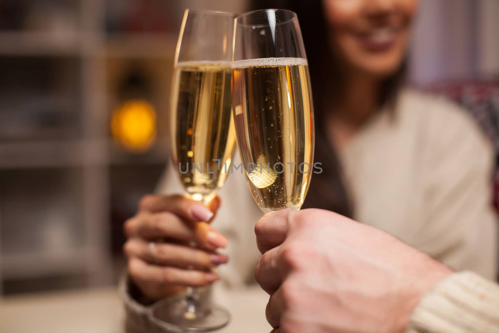 Close up of champagne glasses holded by cheerful couple celebrating christmas.