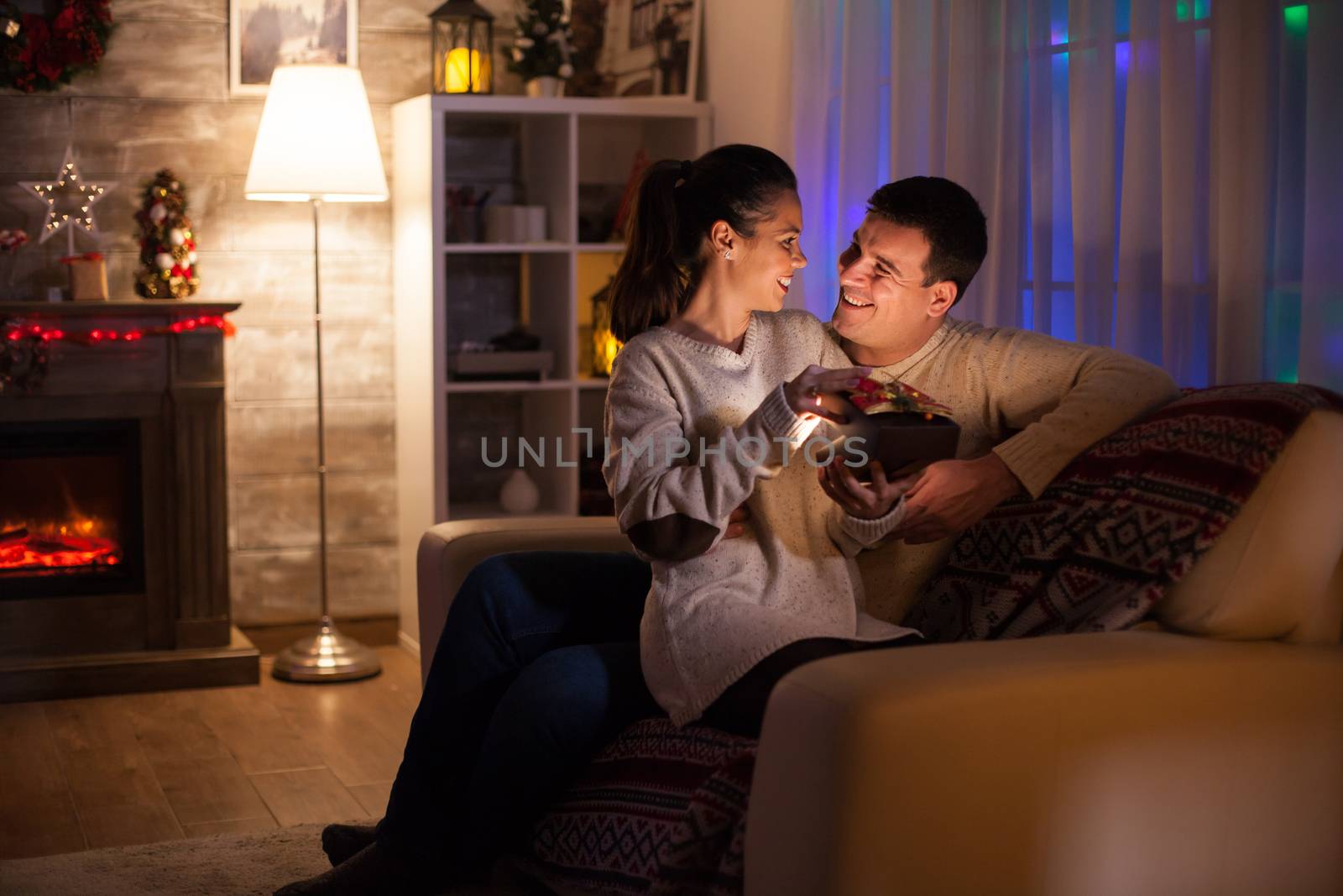 Excited woman in dark living room about her present from her husband.