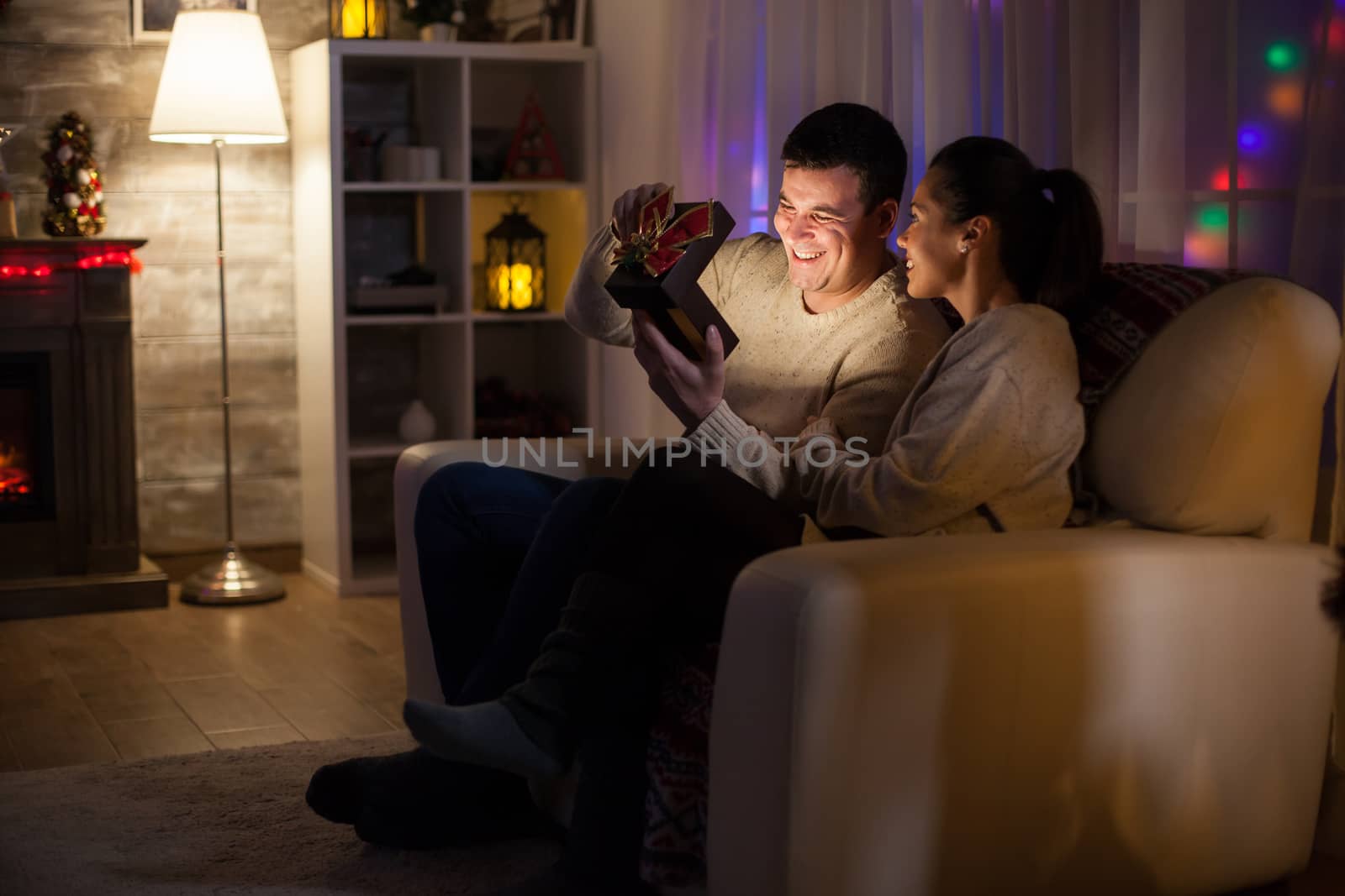 Happy young man with his magical gift from his wife on christmas day sitting on couch.