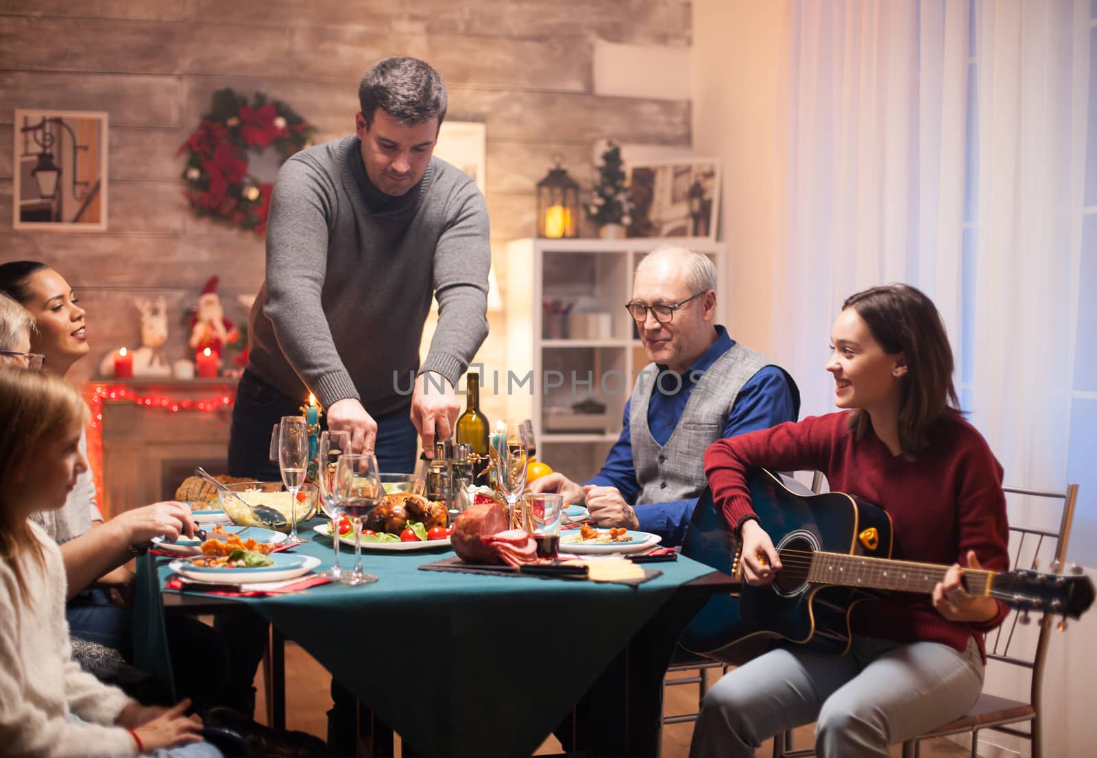 Happy girl singing on her guitar at christmas family celebration.