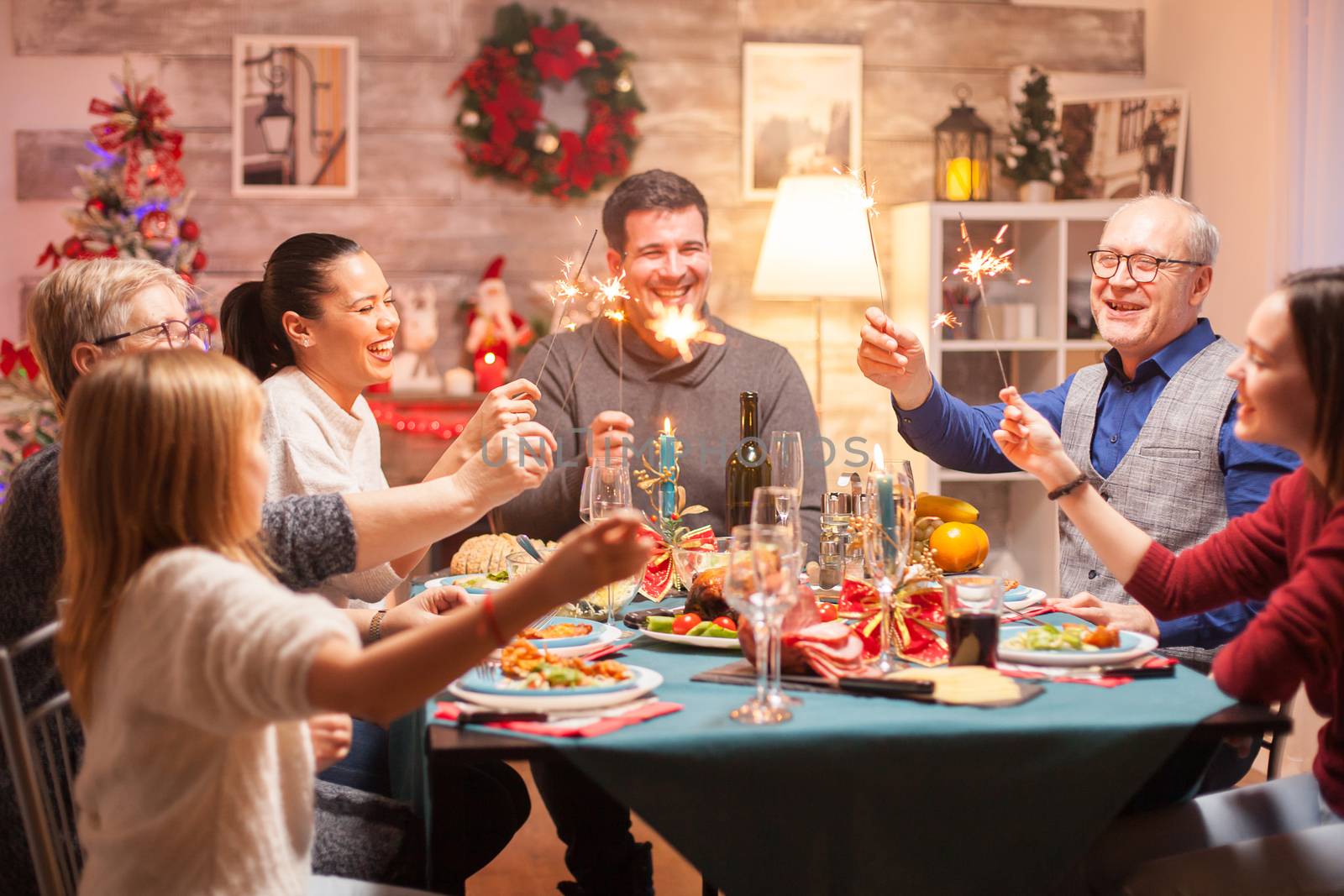 Happy woman holding hand fireworks while celebrating christmas with her family.