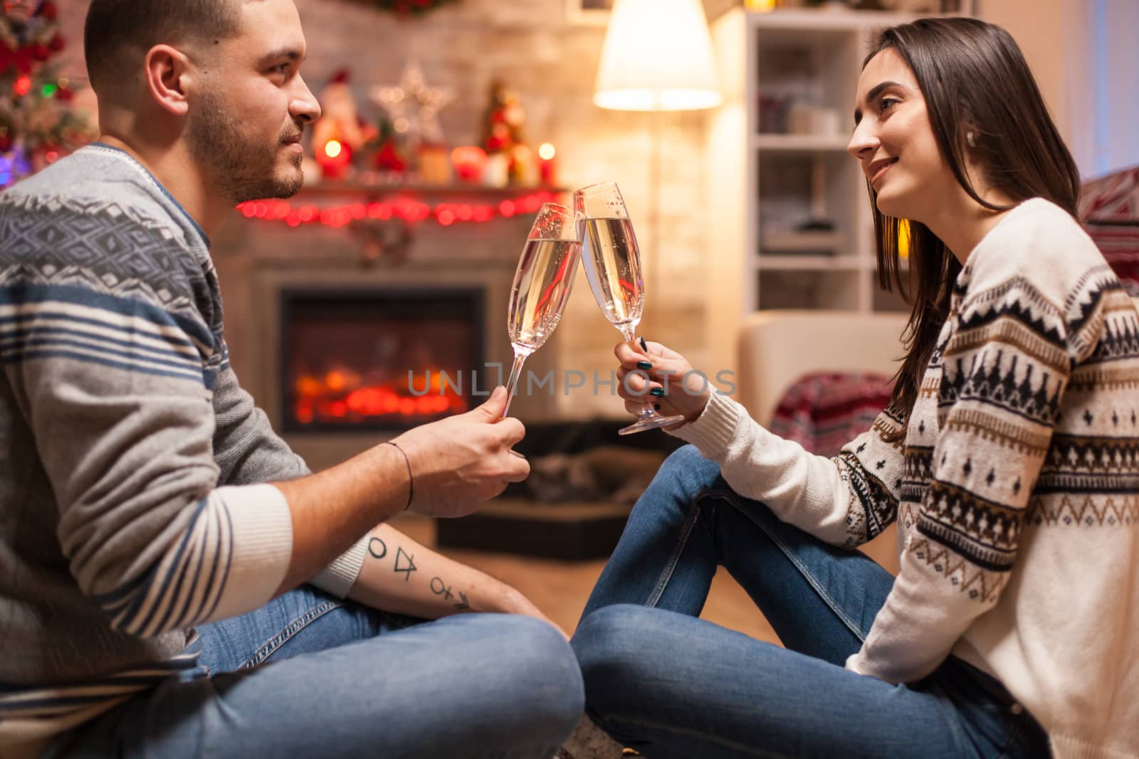 Happy girl thinking how much she loves her boyfriend on christmas day clinking a glass of champagne.