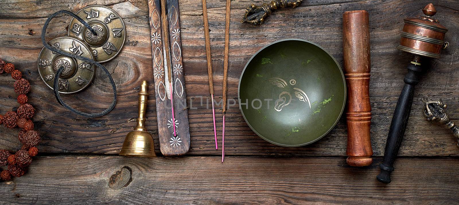 Tibetan singing bowl and other religious ritual instruments for meditation on a brown wooden background, top view