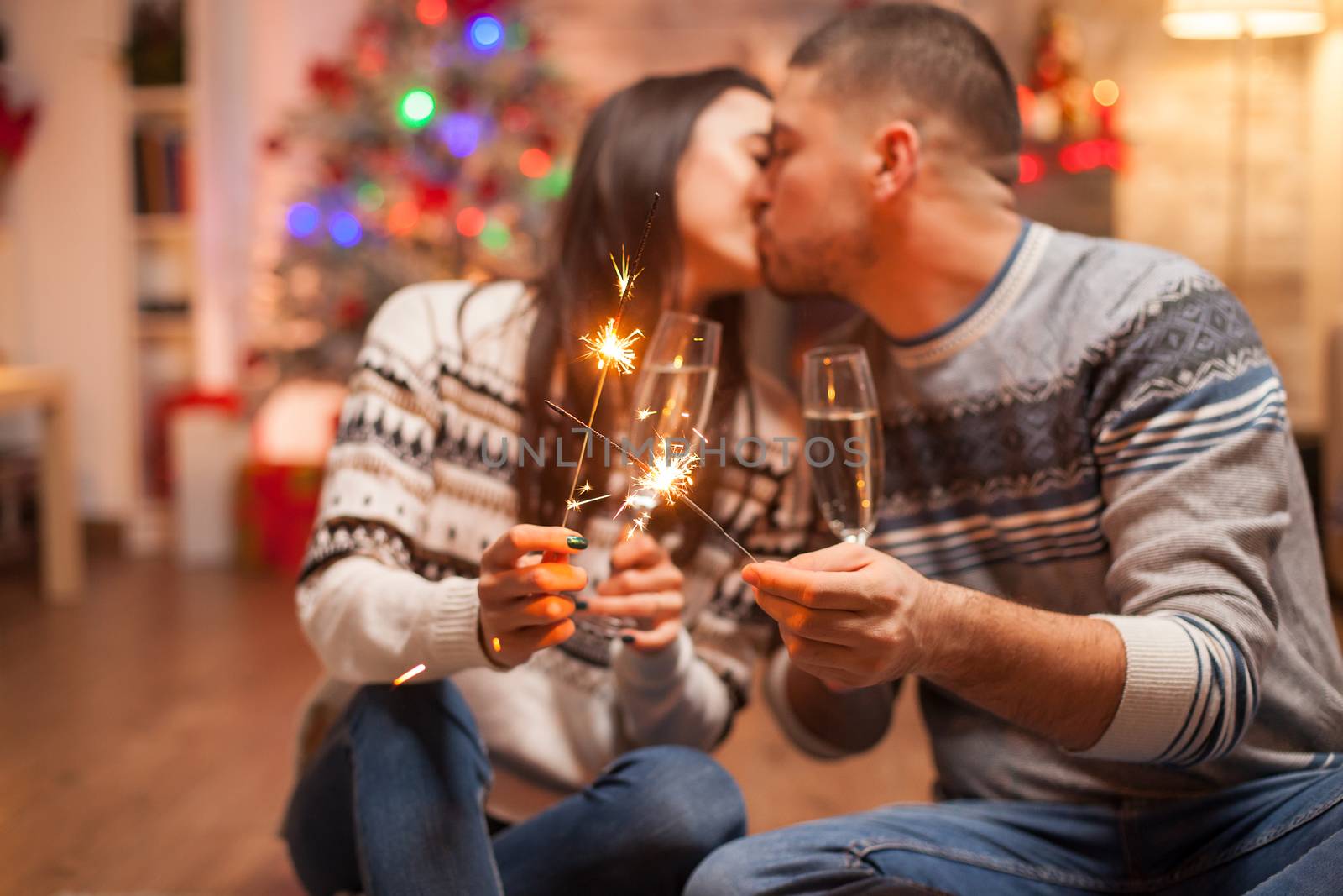 Caucasian couple kissing while holding fireworks on christmas day.