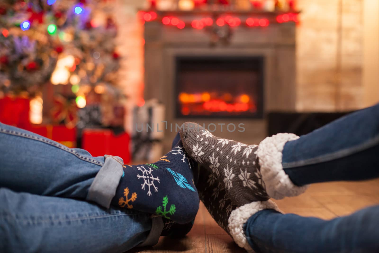Happy young couple keeping their feet together laying on the floor celebrating christmas.