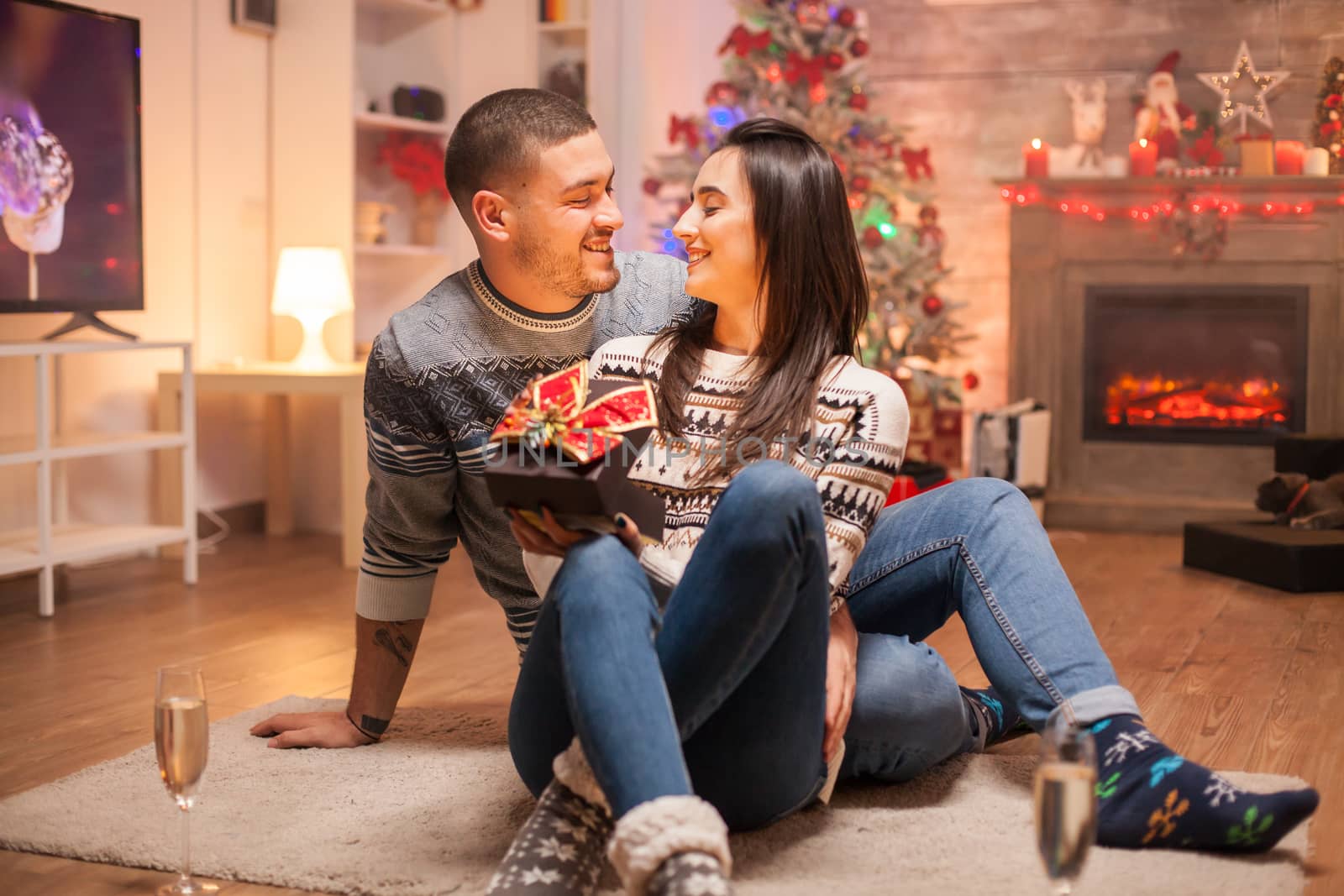 Loving couple with magic gift box celebrating christmas. Warm fireplace.