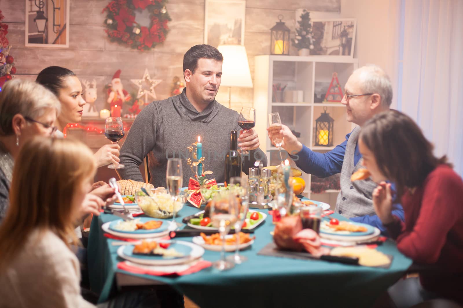 Happy senior man and his son clinking a glass of wine at christmas family dinner.