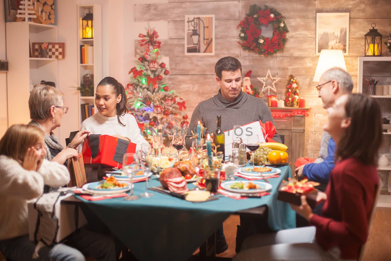 Cheerful woman giving her mother a present at christmas family dinner.