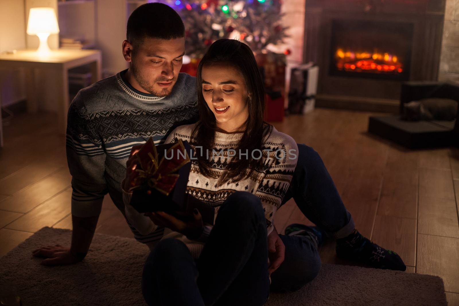Cheerful couple in a dark room excited about about magic christmas gift.