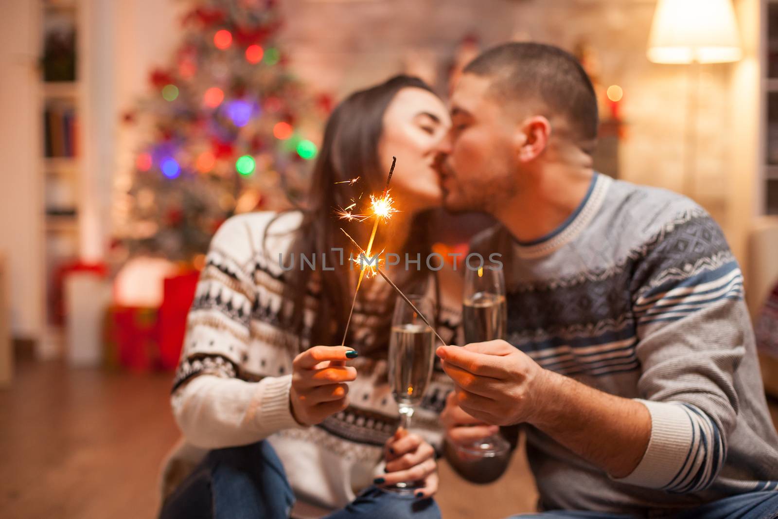 Happy girlfriend kissing his boyfriend while holding a hand fireworks by DCStudio