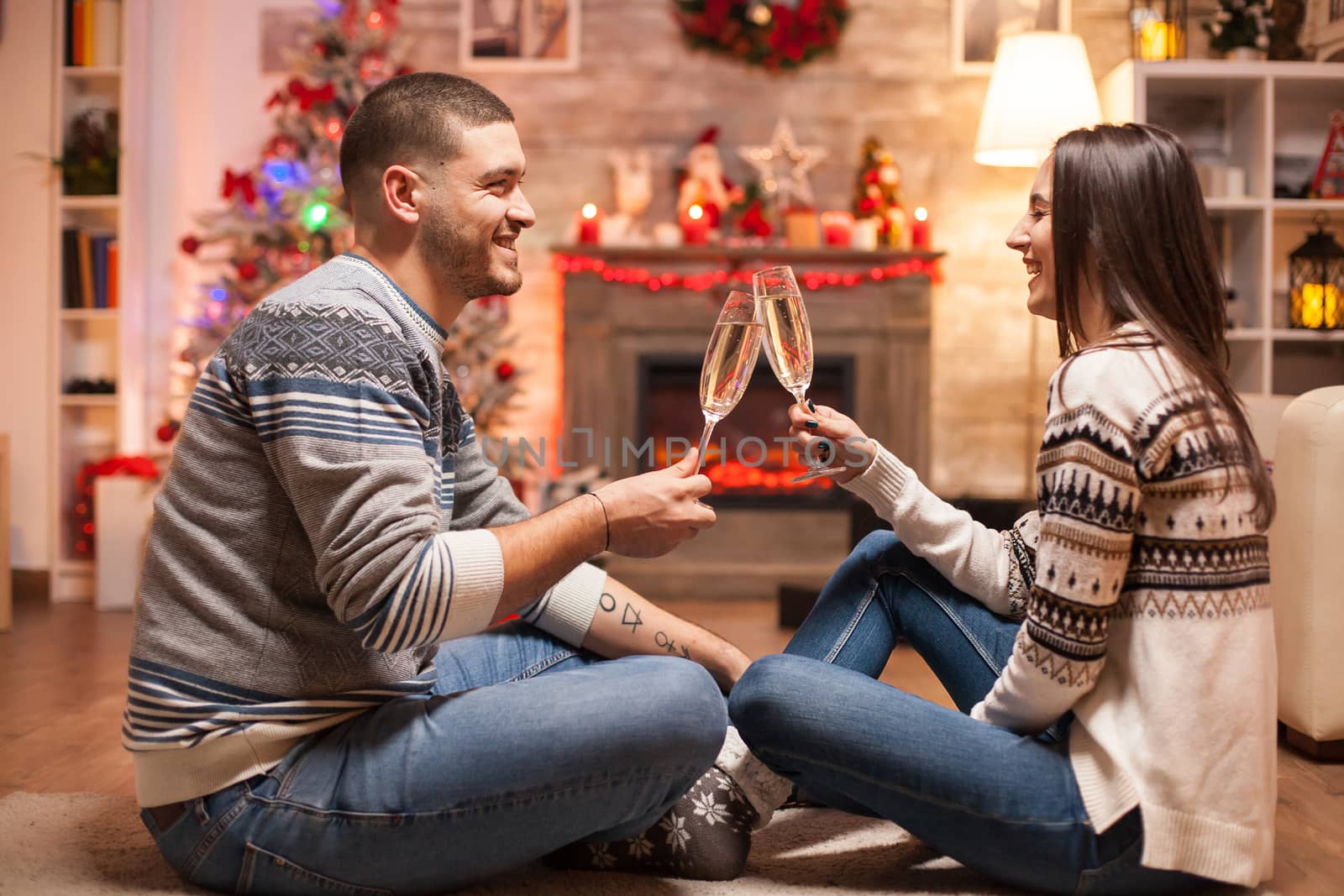 Cheerful couple laughing while clinking a glass of champagne celebrating christmas.