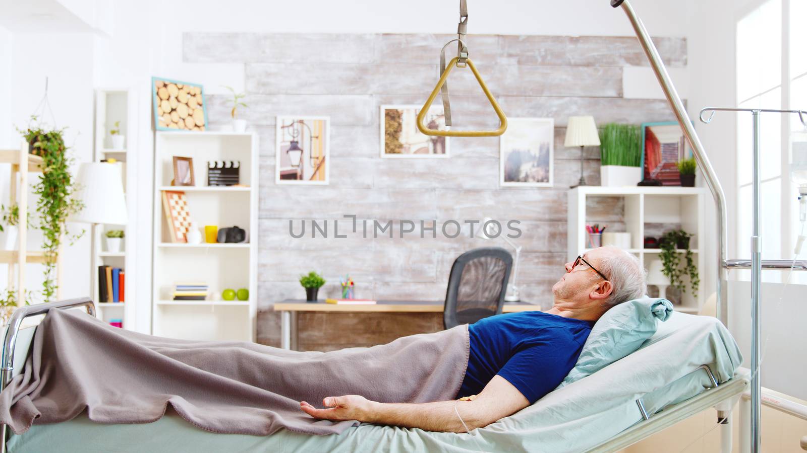 Old retired and disabled man lying in a hospital bed in a nursing home by DCStudio