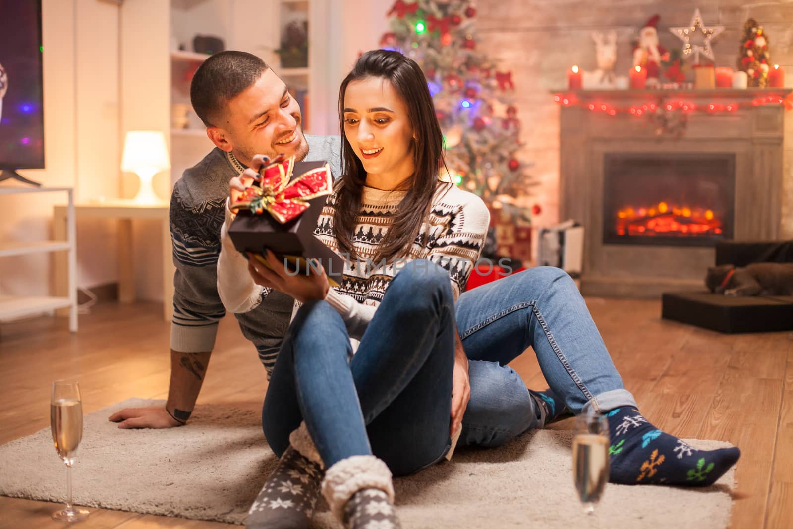 Cheerful man giving her girlfriend a magic gift on christmas day.