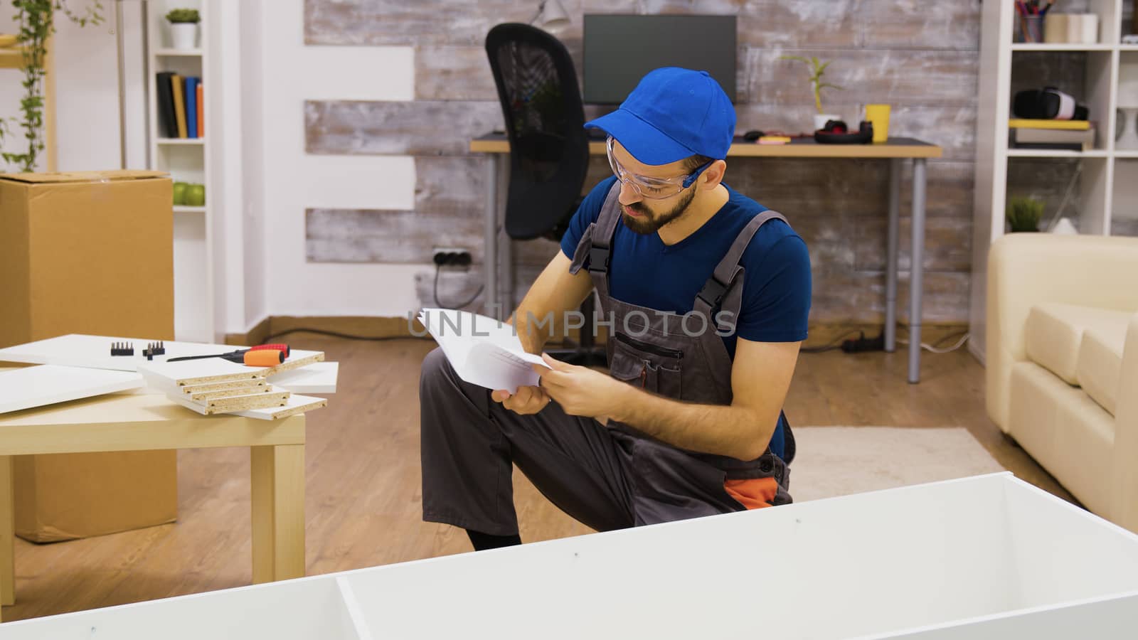 Male worker wearing protection glasses before furniture assembly by DCStudio
