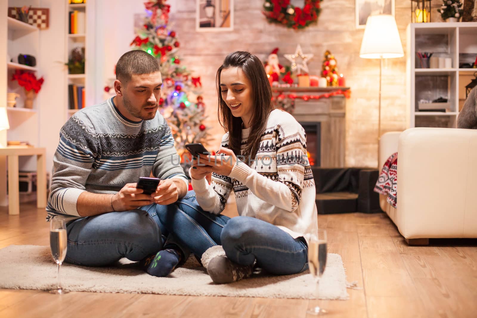 Romantic couple in matching clothes doing online shopping on their smartphone for christmas.