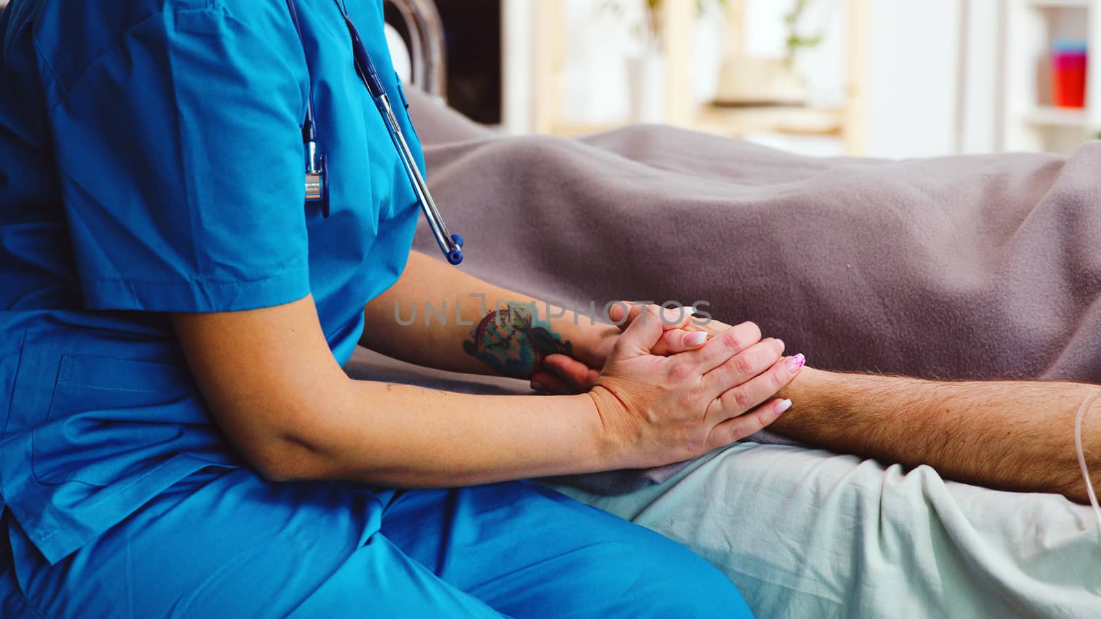 Close up shot of nurse taking old man hands lying in hospital bed