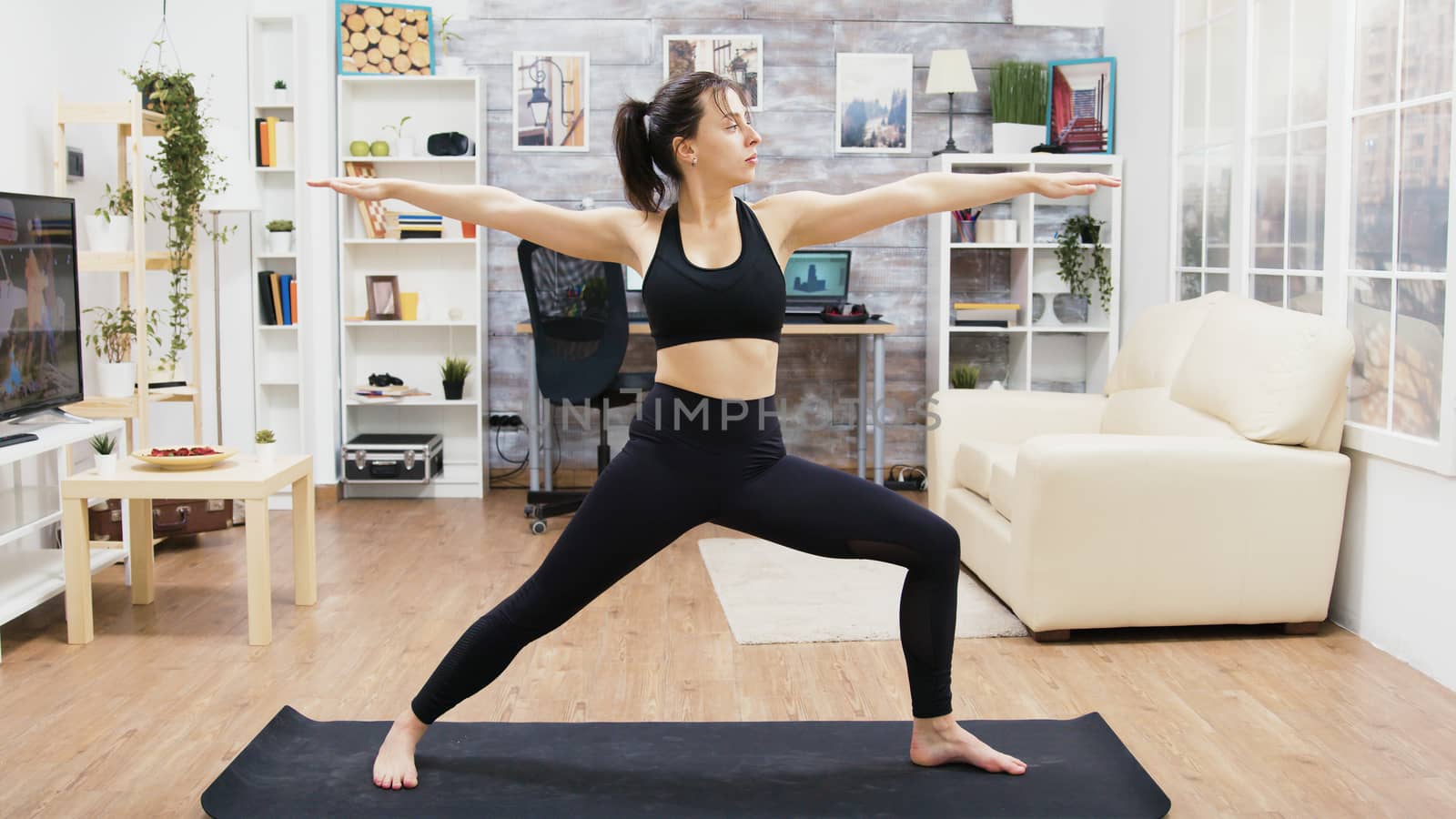 Calm young female practicing yoga exercises in living room by DCStudio