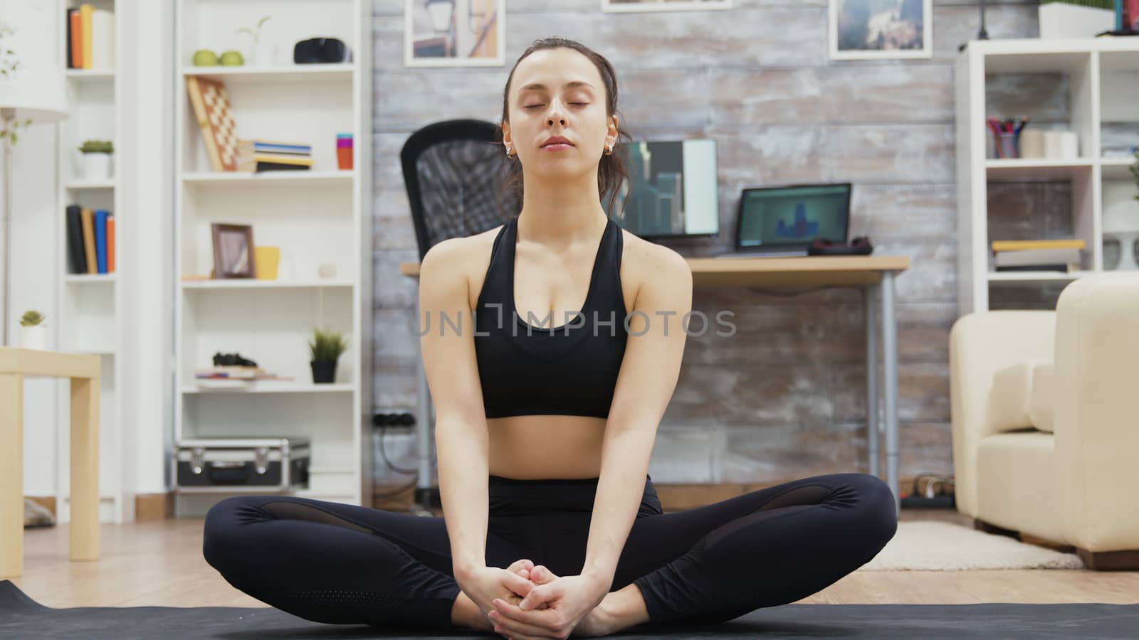 Zoom in shot of beautiful young woman smiling doing yoga meditation in living room.