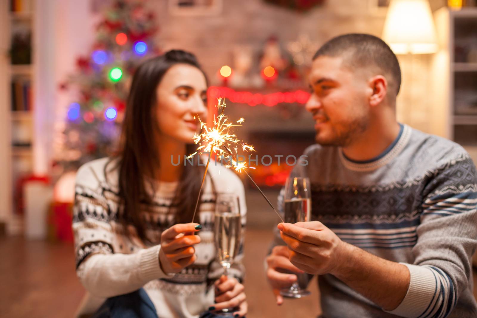 Cheerful young couple holding hand fireworks celebrating christmas.