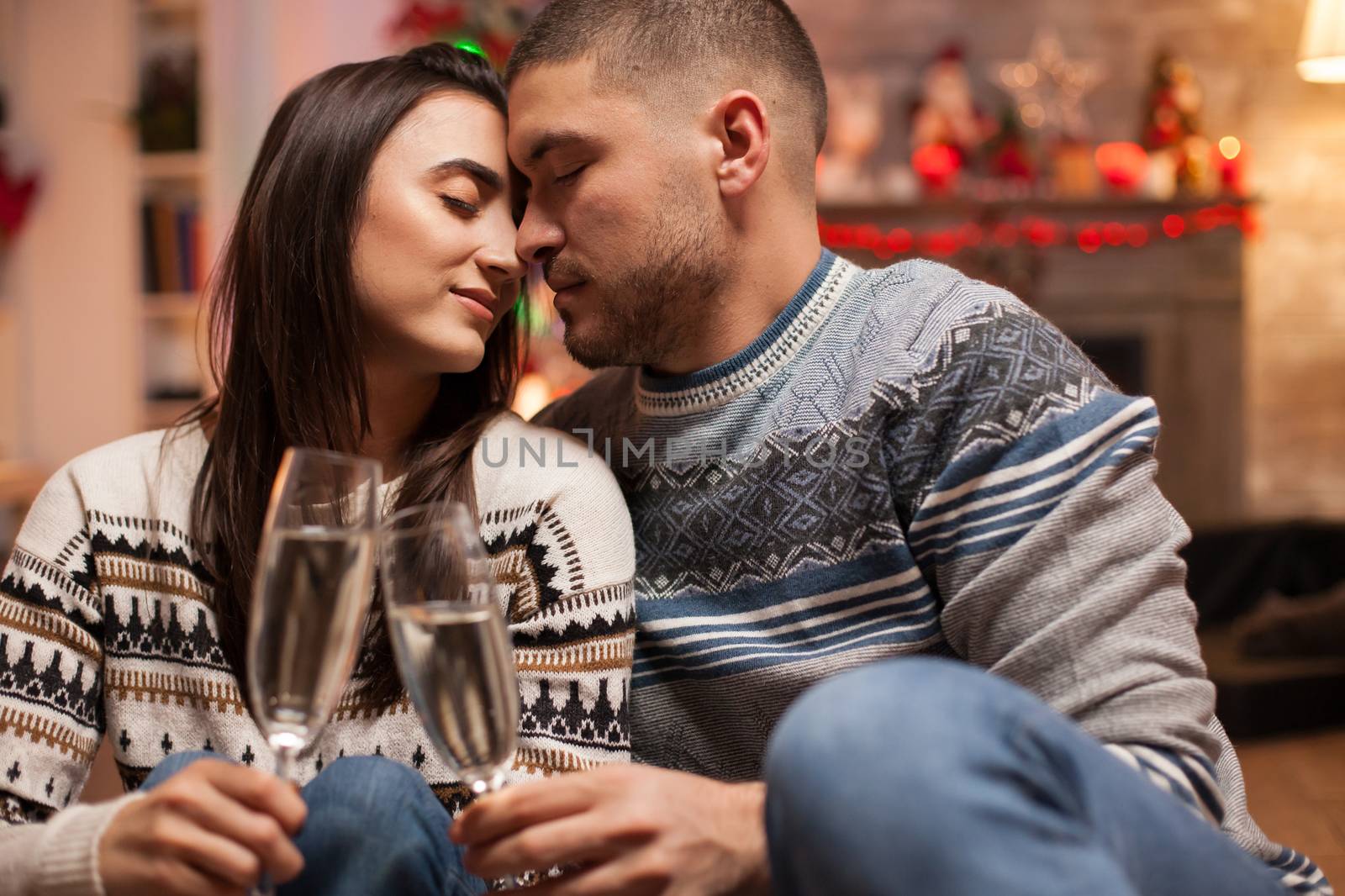 Loving couple keeping their eyes closed on christmas day while holding glasses of champagne.