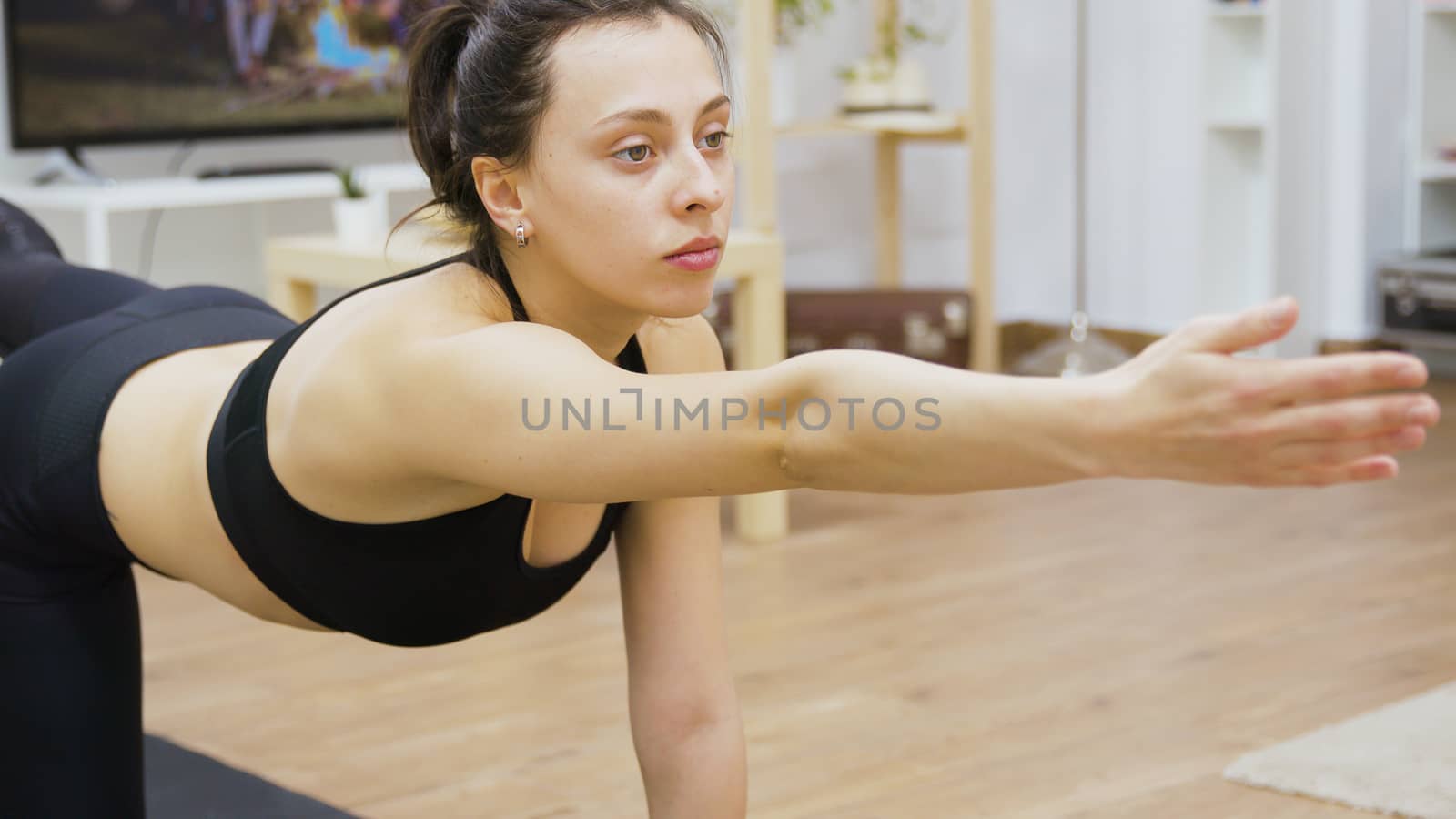 Attractive young woman in sportswear working out on yoga mat in living room.