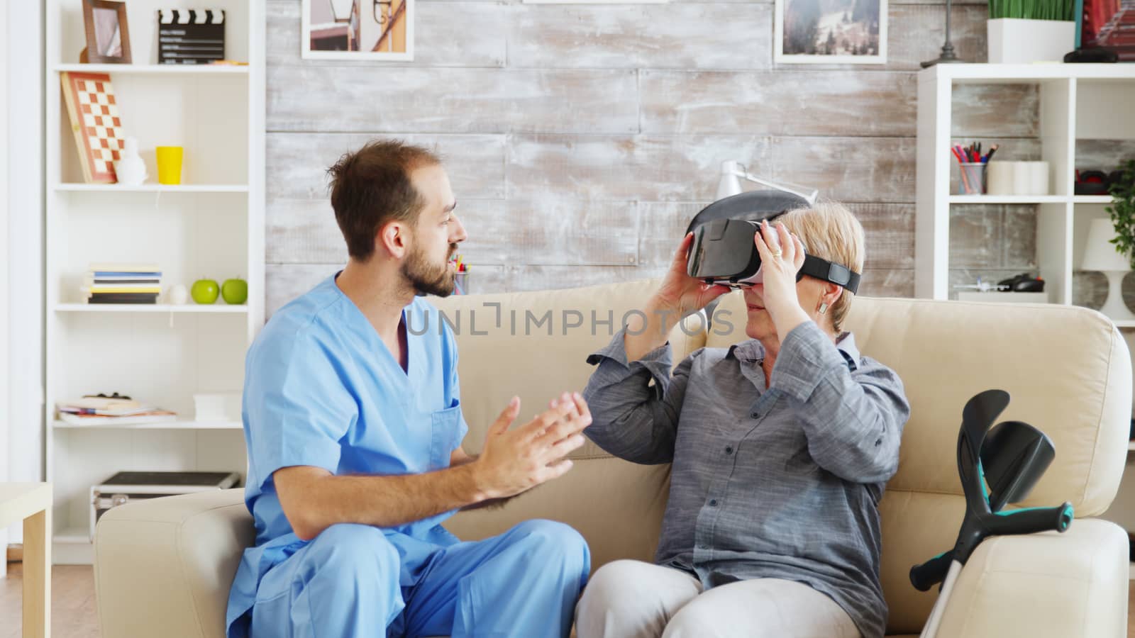Male doctor in nursing home helping senior woman to use virtual reality goggles