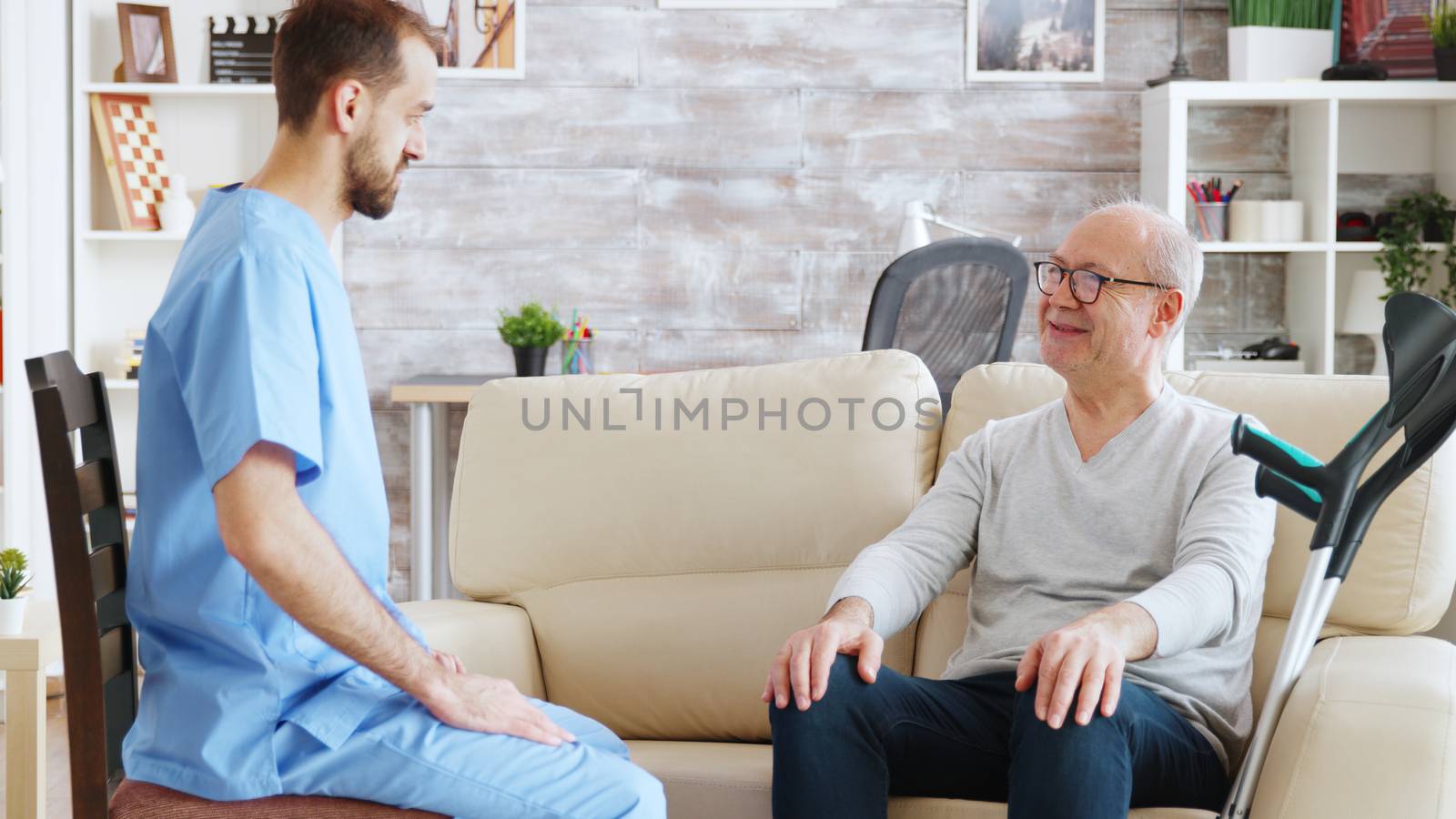 Retired pensioner in nursing home talking with a male nurse by DCStudio