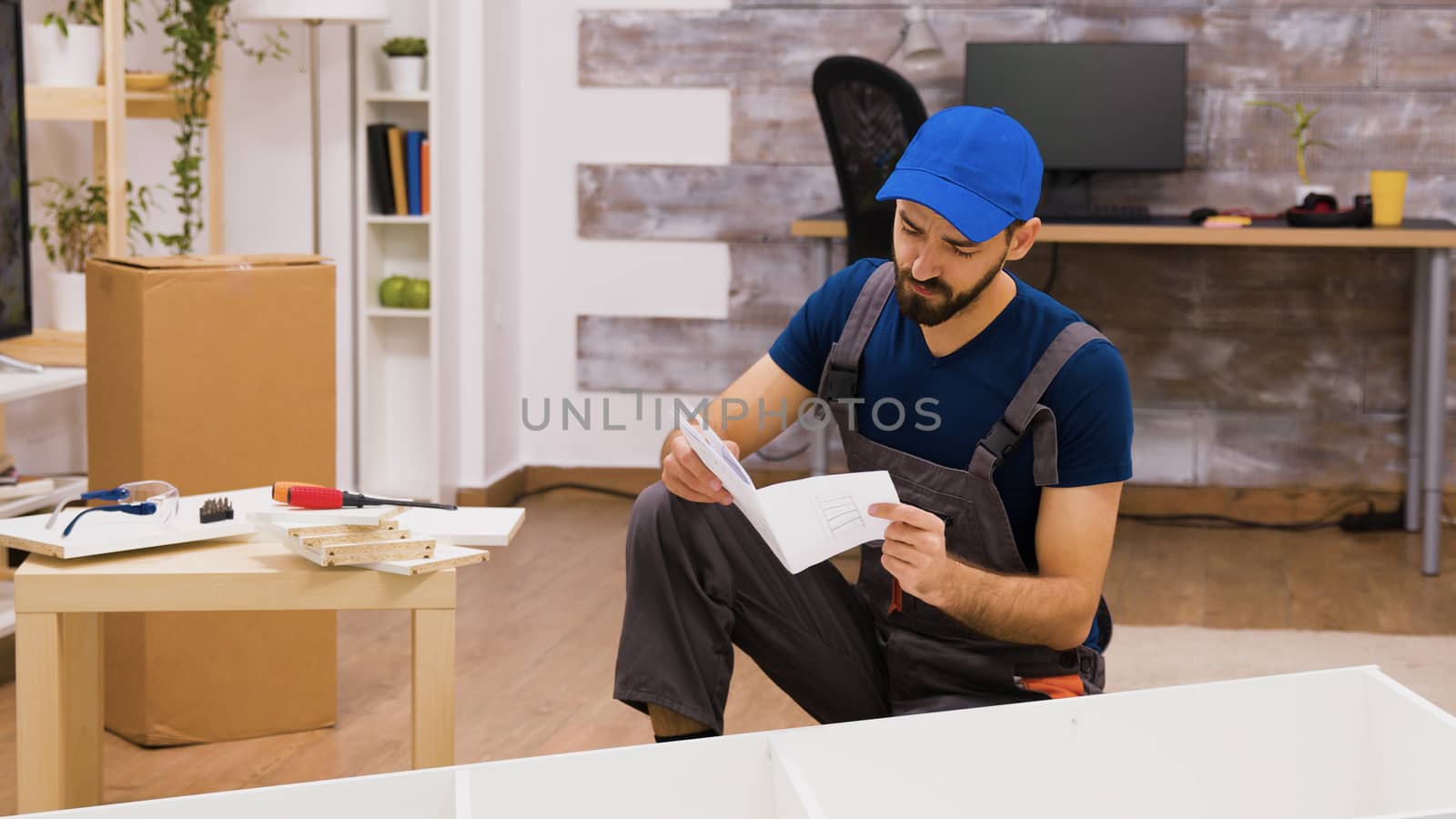 Confused furniture assembly worker while reading instructions to mount a shelf.