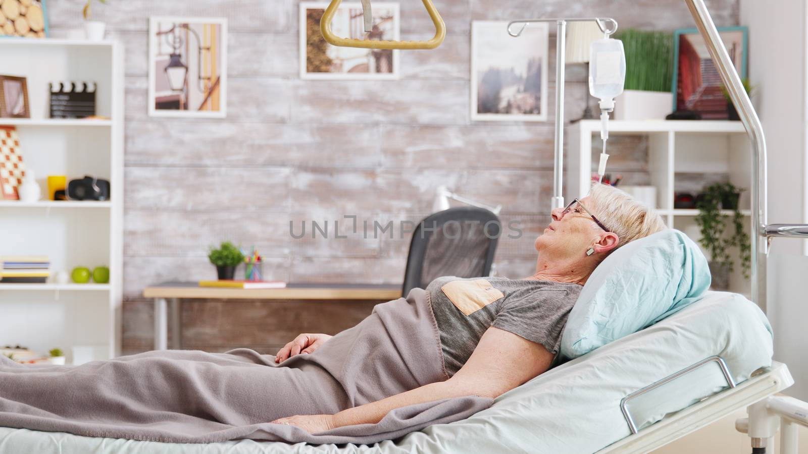 Old lady lying on hospital bed in nursing home by DCStudio