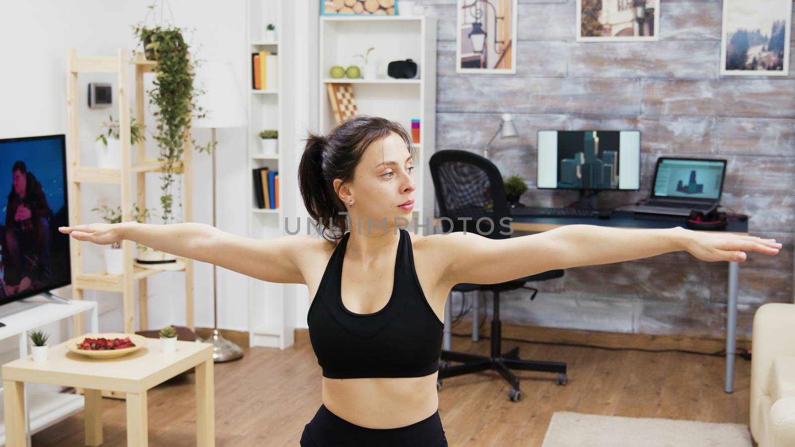 Young woman doing sports at home in living room. Woman standing on yoga pose.