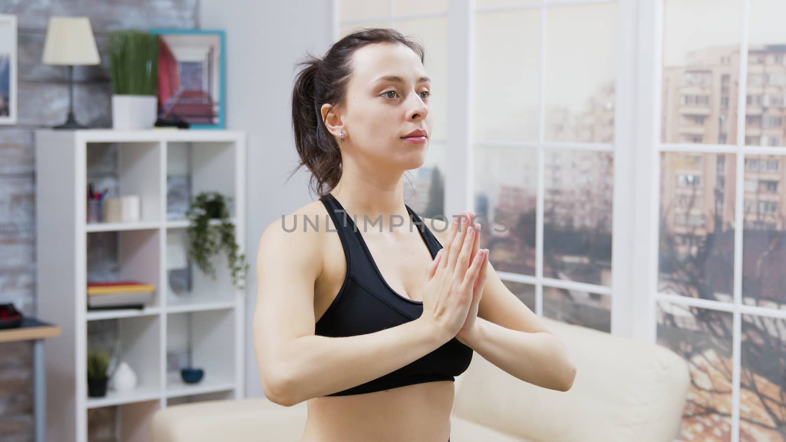 Young woman smiling while doing yoga in living room. Body relaxation.