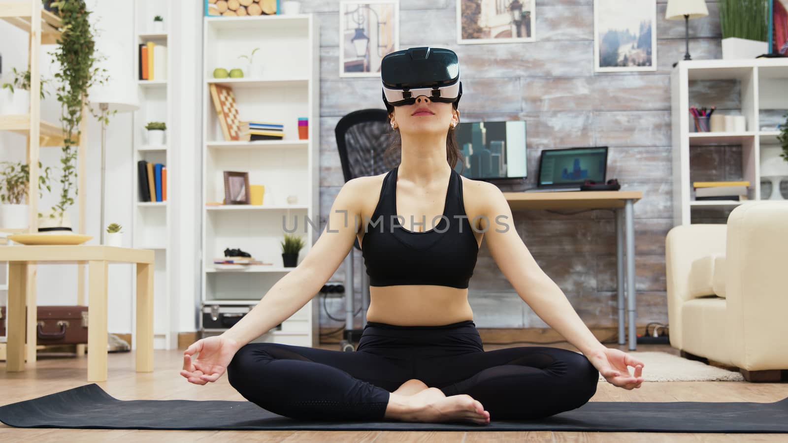 Beautiful young woman wearing virtual reality glasses doing yoga by DCStudio
