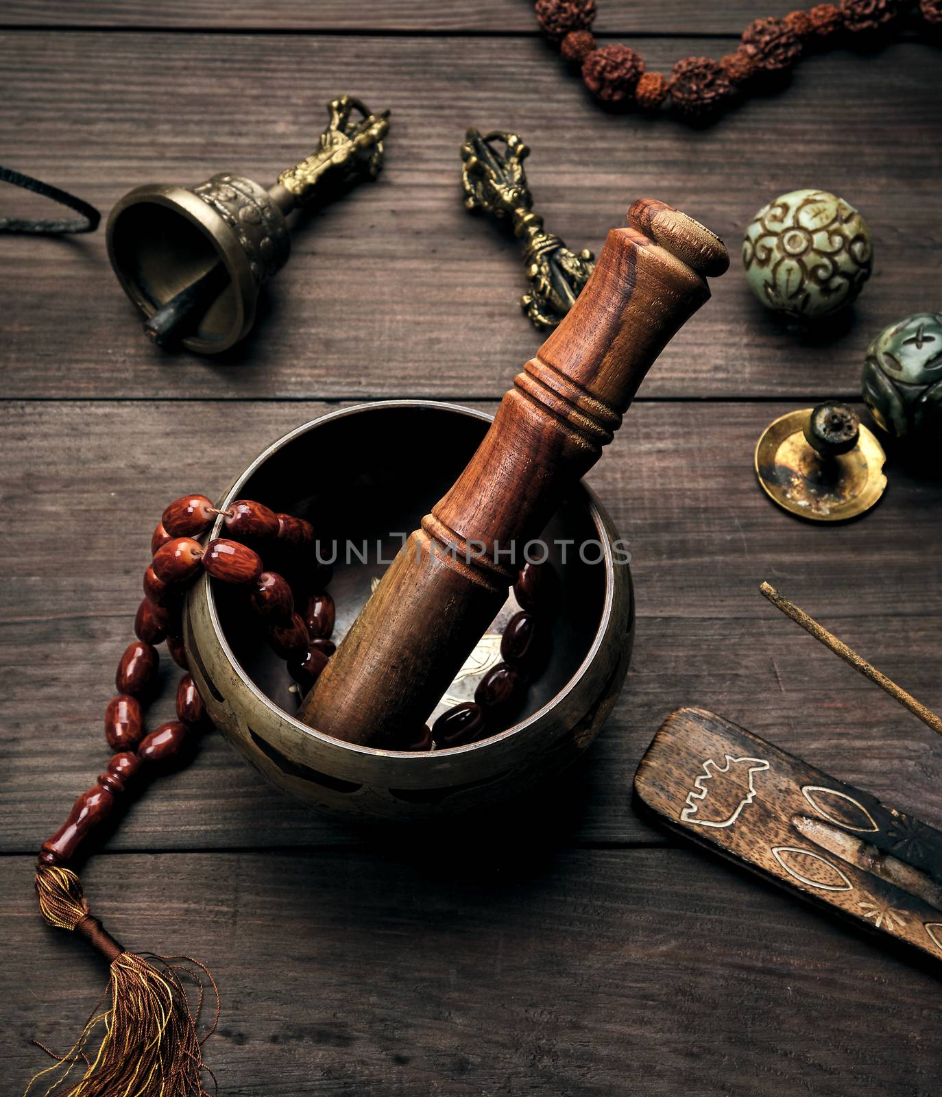 copper singing bowl and a wooden stick on a brown table,  top view