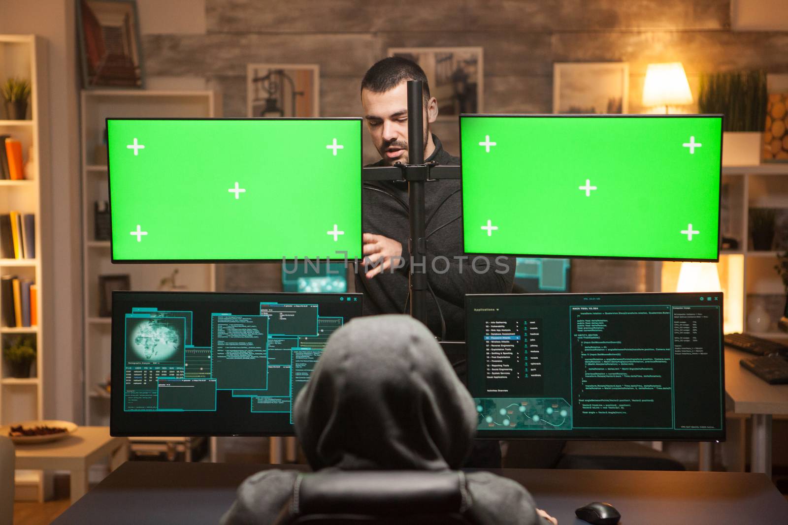 Back view team of hackers doying cyber attacks in front of computer with green screens.
