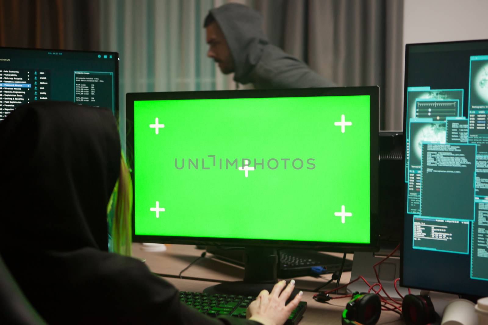 Organised female hacker in front of computer with green screen.