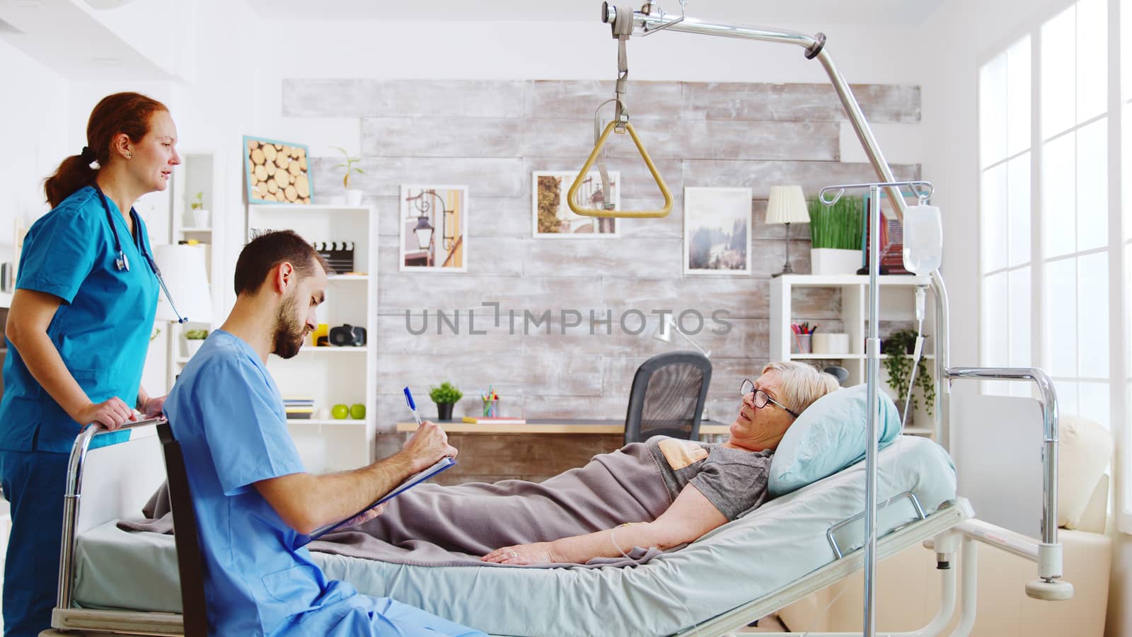 Team of male and female nurses checking an old lady lying in hospital bed in a retirement home