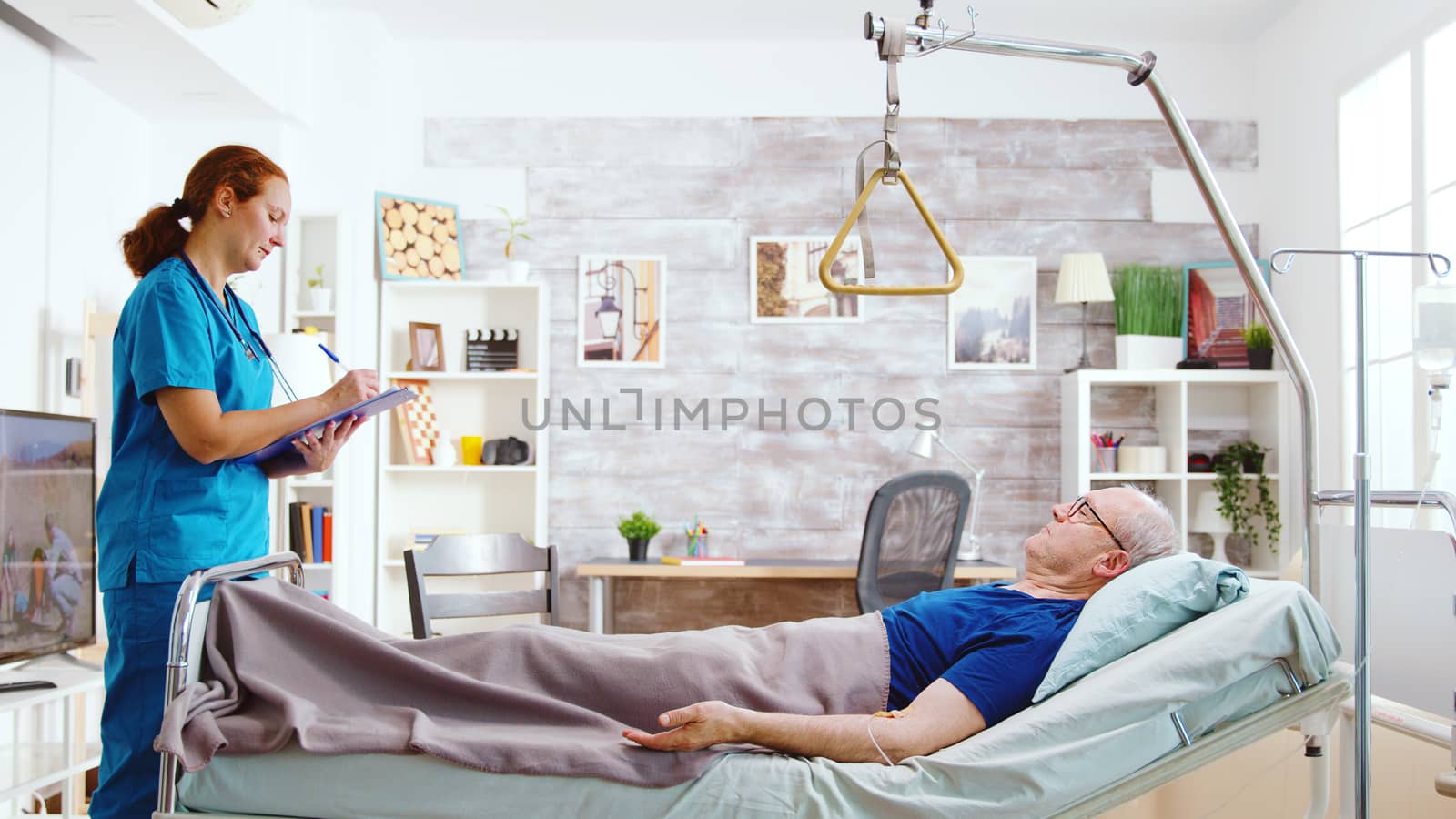 Nurse checking on old and sick patient lying in hospital bed by DCStudio