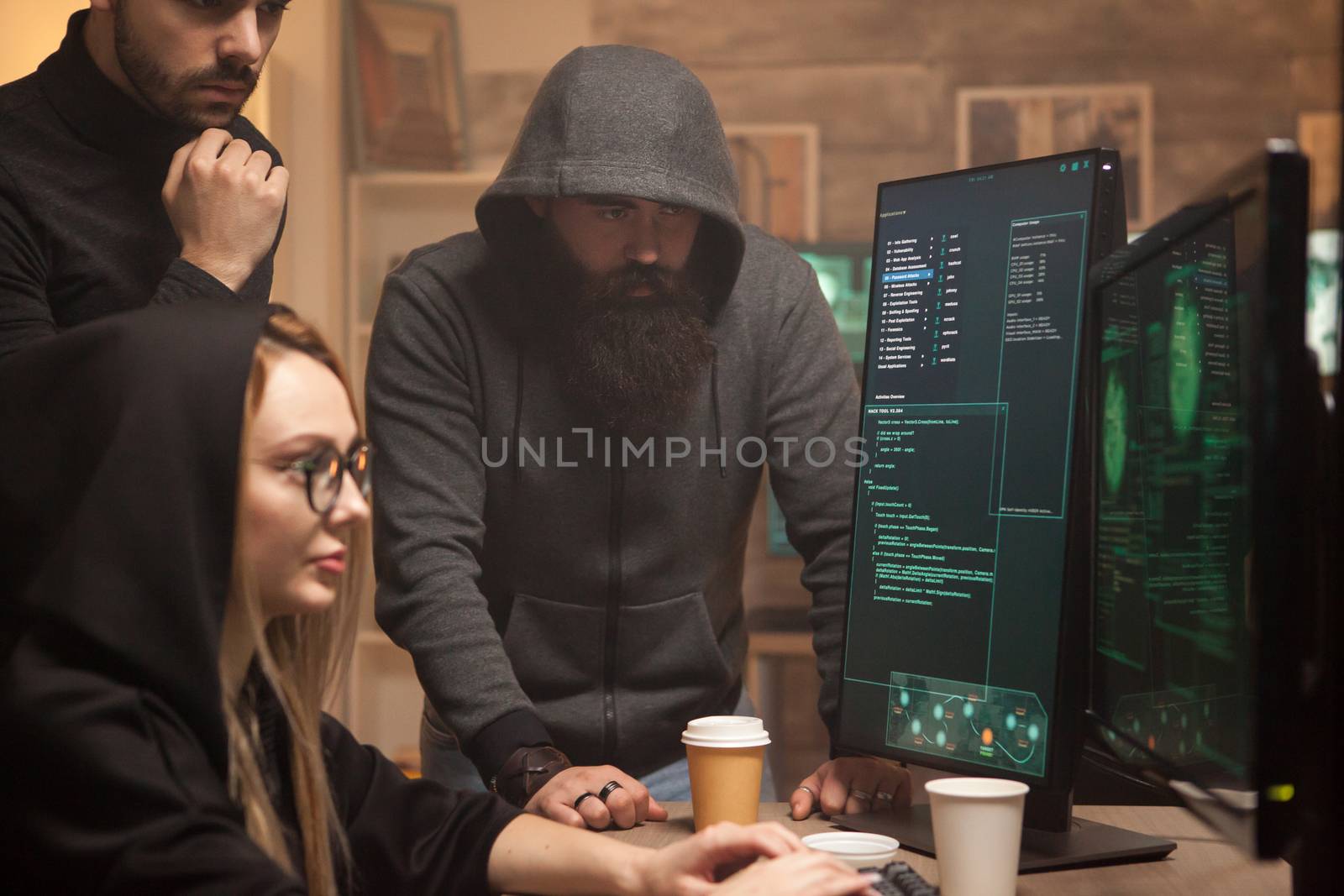 Bearded hacker wearing a hoodie while his team breaks vulnerable government servers.