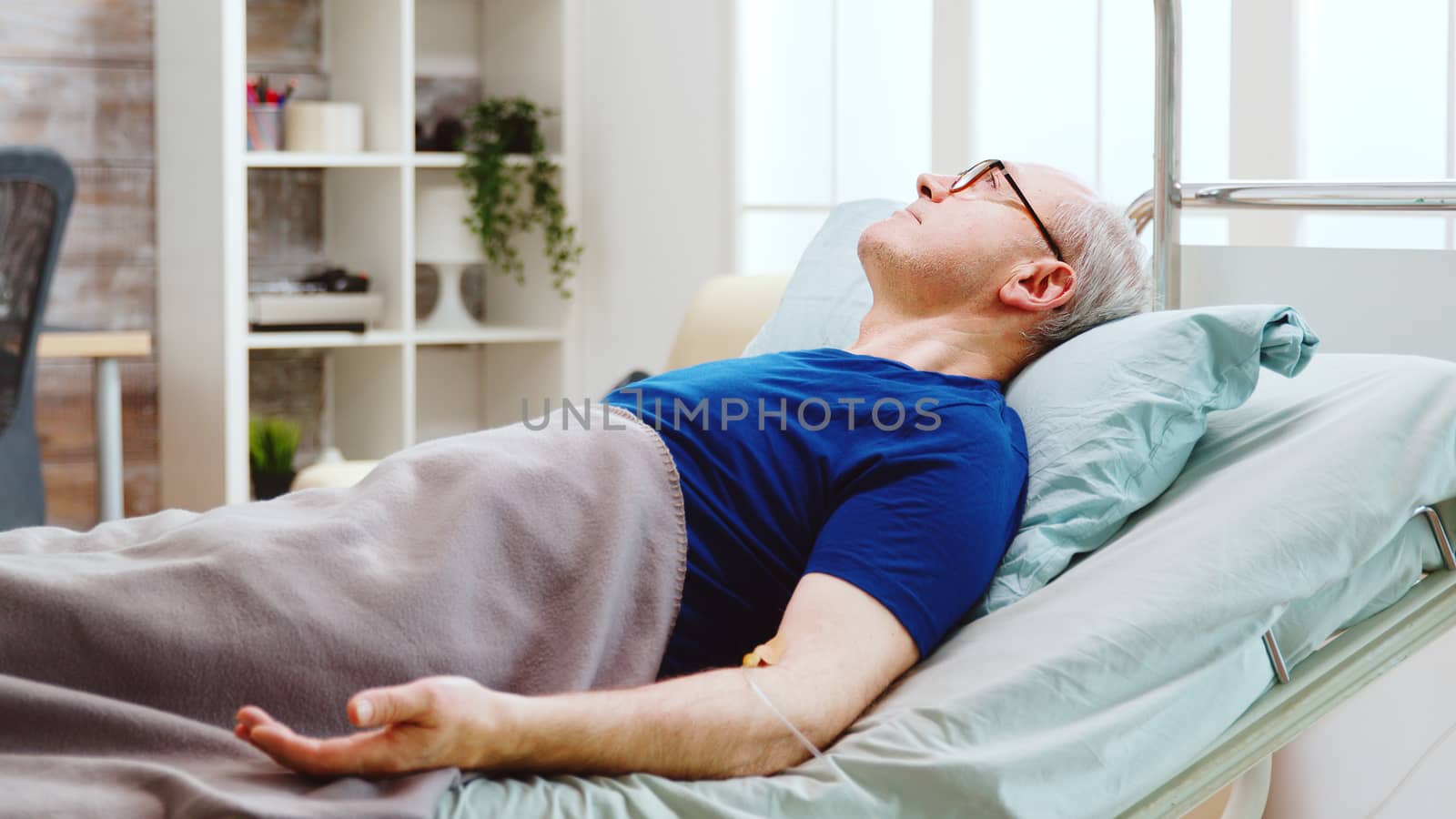 Portrait of elderly sick man lying in hospital bed by DCStudio