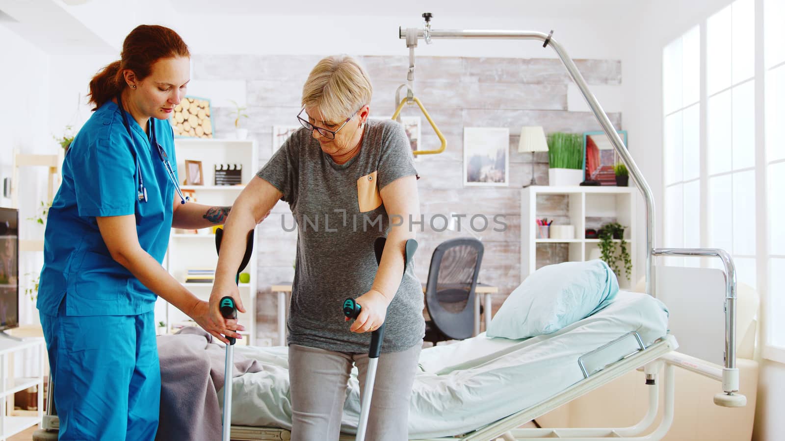 Nurse in retirement home helping an elderly woman to recover her muscle strength. Physiotherapy and social worker