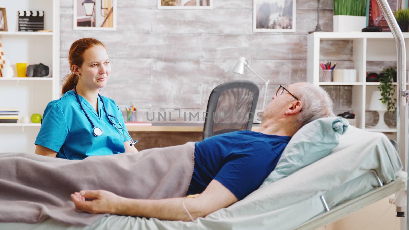 Sick elderly man having a conversation with a caucasian nurse while lying in a hospital bed in a nursing home