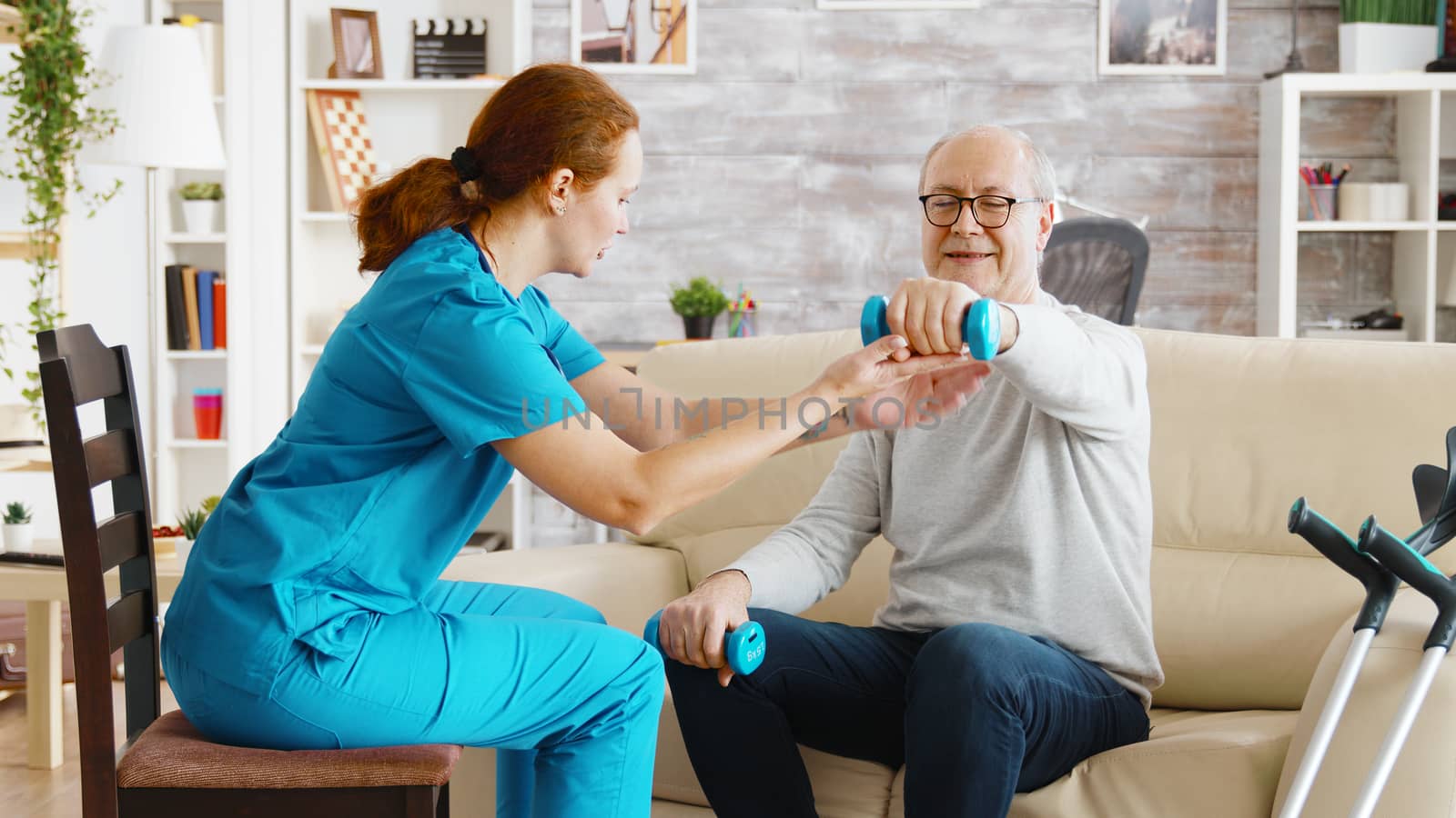 Female nurse helps an old man to make his morning exercises by DCStudio