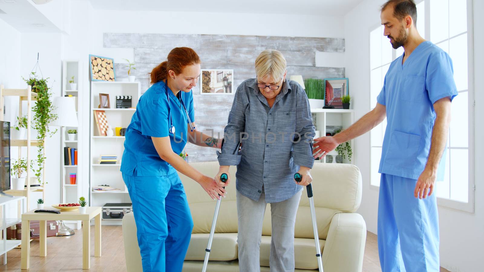 Senior woman with crutches getting help for female nurse by DCStudio