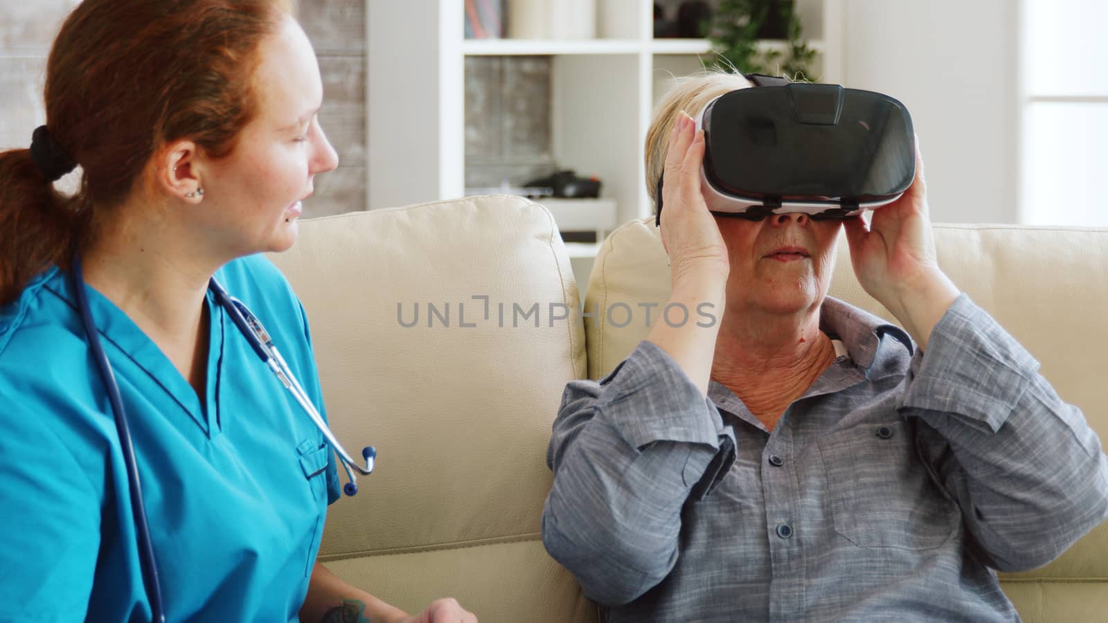Female nurse helping senior woman to experience virtual reality with vr goggles in nursing home