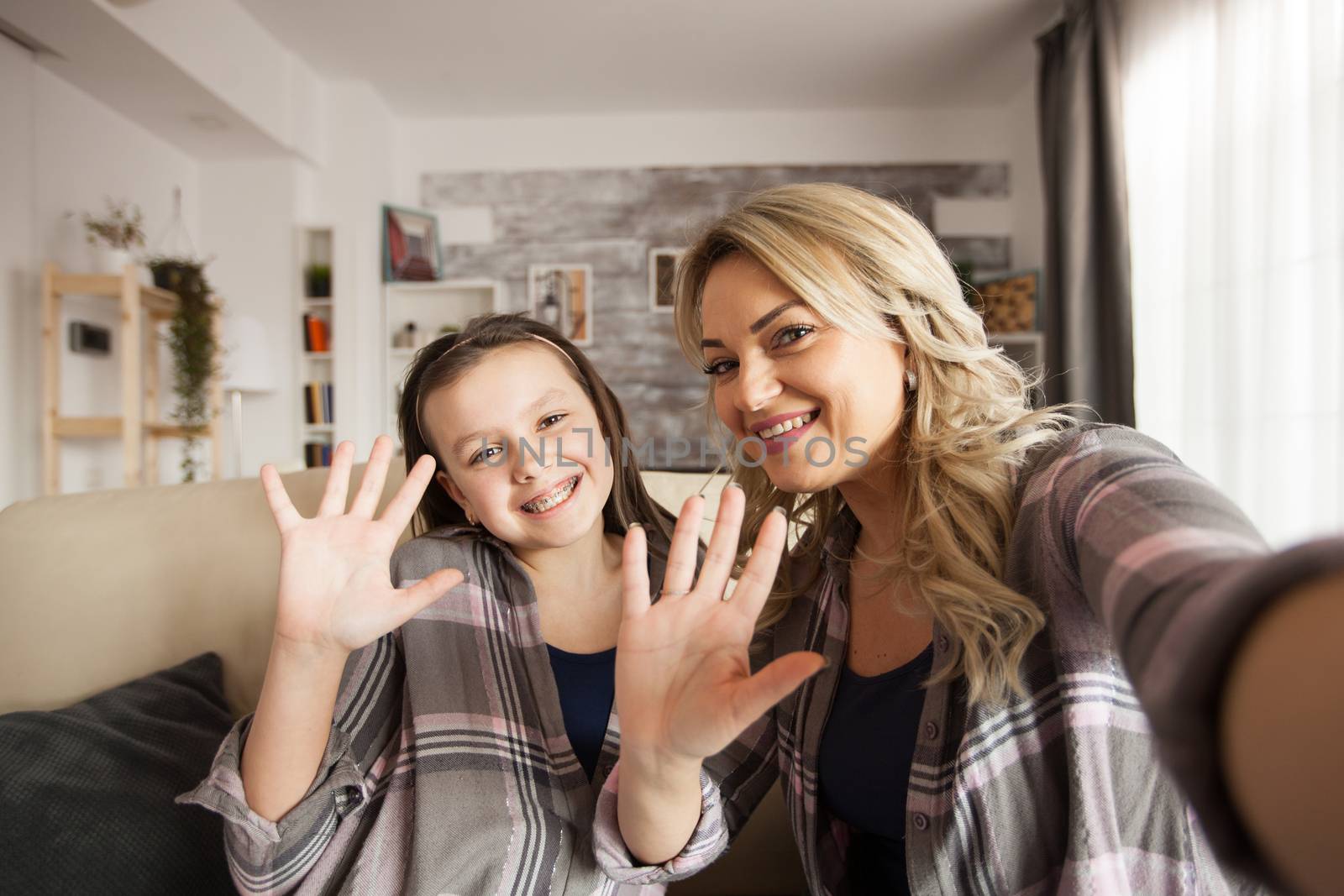 Pov of little girl with braces with and her mother waving to the camera.