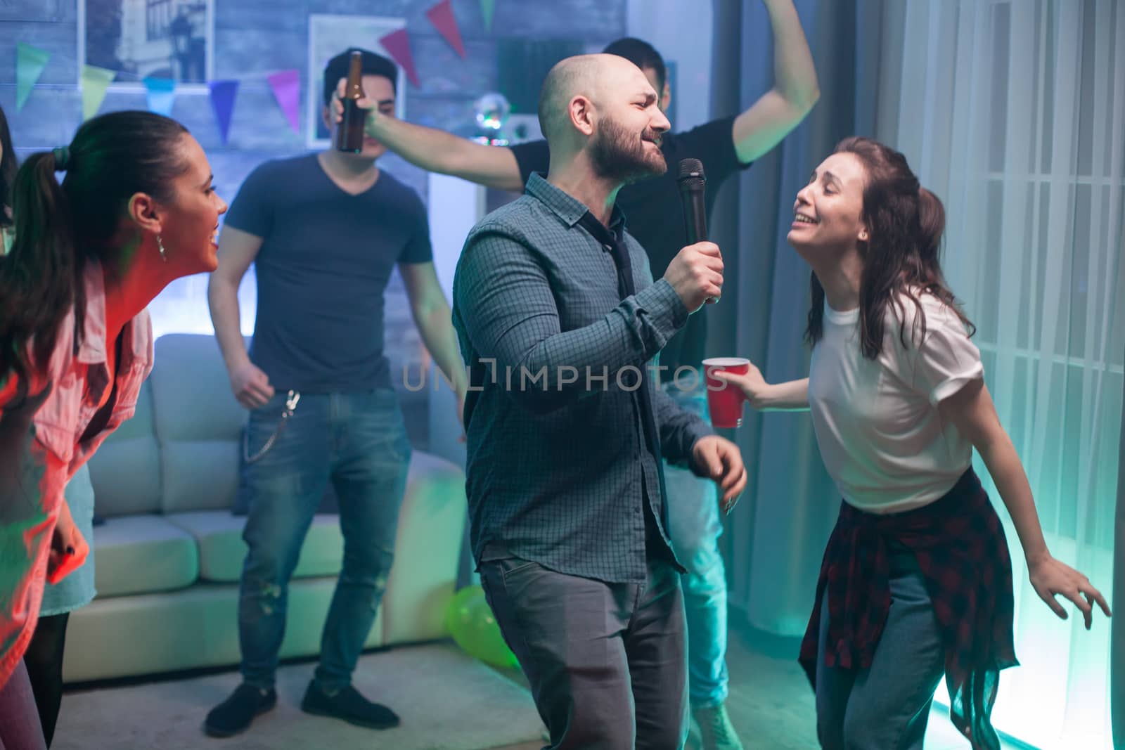 Young man and his best friend singing on microphone at the party.