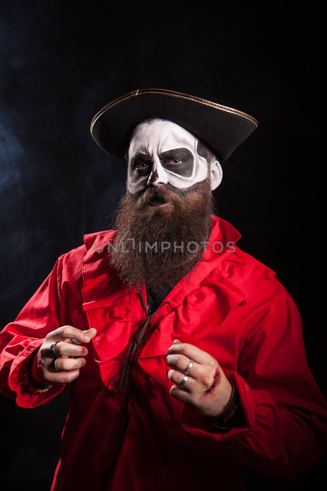 Man with long beard dressed up like medieval pirate over black background for halloween.