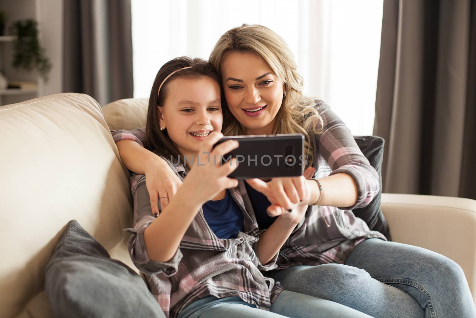 Beautiful young mother and her daughter are using a smartphone by DCStudio