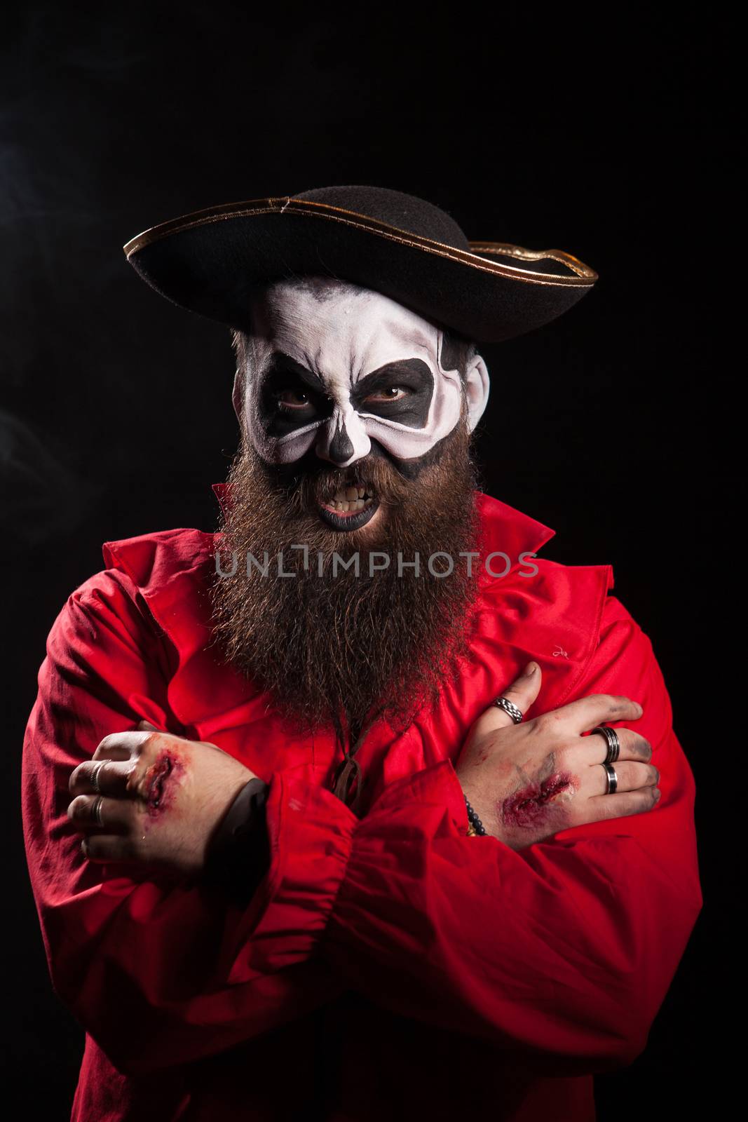 Evil bearded pirate with spooky makeup for halloween over black background.
